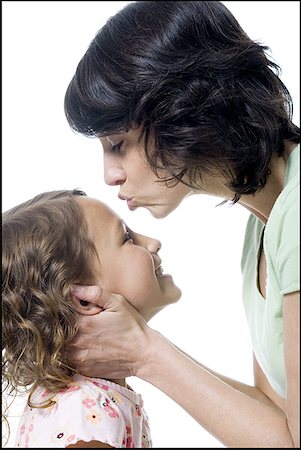 Close-up of a mid adult woman kissing her daughter's forehead Stock Photo - Premium Royalty-Free, Code: 640-01349396