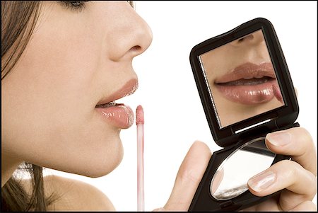 Closeup of woman applying lipstick with compact mirror Fotografie stock - Premium Royalty-Free, Codice: 640-01349599