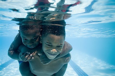 friend playing piggyback - Boys swimming underwater in pool Stock Photo - Premium Royalty-Free, Code: 640-01349733