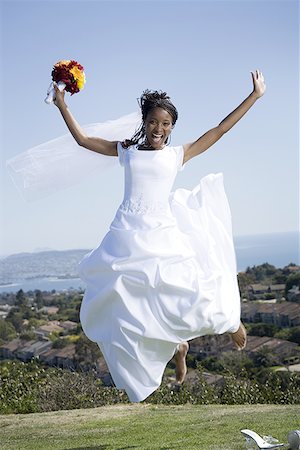 Portrait of a bride holding a bouquet of flowers and jumping Stock Photo - Premium Royalty-Free, Code: 640-01349772
