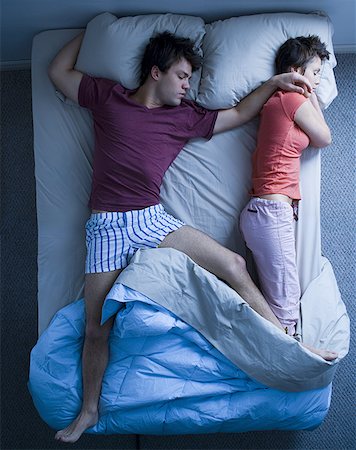 simsearch:640-01355958,k - Man stretched out on bed with woman sleeping Fotografie stock - Premium Royalty-Free, Codice: 640-01349865
