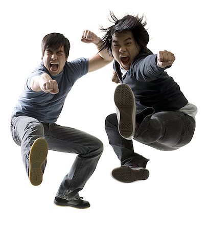 eyes closed portrait of asian man - Portrait of two young men jumping and kicking Stock Photo - Premium Royalty-Free, Code: 640-01349890