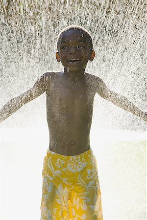 Boy standing in front of a spray of water Stock Photo - Premium Royalty-Free, Code: 640-01349935