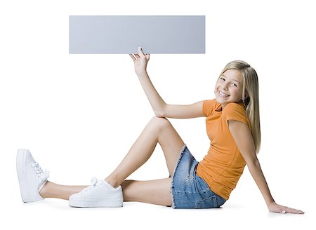 Portrait of a girl sitting on the floor and holding a blank sign Stock Photo - Premium Royalty-Free, Code: 640-01349970
