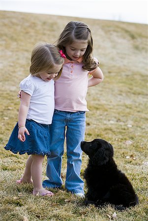 sister hugs baby - Deux jeunes filles s'enlaçant avec chiot à l'extérieur Photographie de stock - Premium Libres de Droits, Code: 640-01354106