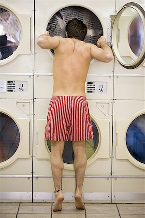 Man in boxers looking in dryer at Laundromat Foto de stock - Sin royalties Premium, Código: 640-01354174