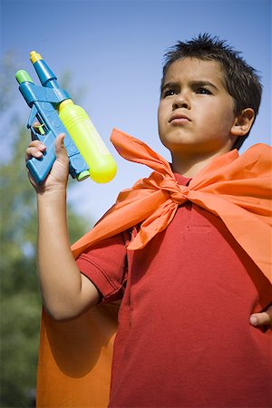 Low angle view of a boy holding a squirt gun Stock Photo - Premium Royalty-Free, Code: 640-01354216