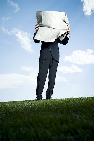 Businessman standing on the grass and reading a newspaper Stock Photo - Premium Royalty-Free, Code: 640-01354331