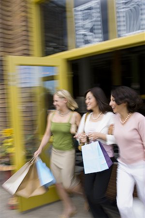 Two young women with an adult woman stepping out of a store Stock Photo - Premium Royalty-Free, Code: 640-01354439