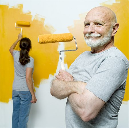 Portrait d'un homme senior tenant un rouleau de peinture avec une femme senior peignant un mur Photographie de stock - Premium Libres de Droits, Code: 640-01354498