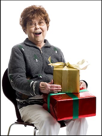 Portrait of a senior woman sitting on a chair and holding gifts Stock Photo - Premium Royalty-Free, Code: 640-01354610