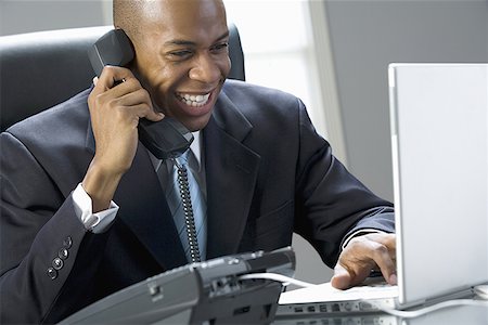 photos of black people in a computer class - Close-up of a businessman smiling and talking on the phone Stock Photo - Premium Royalty-Free, Code: 640-01354707