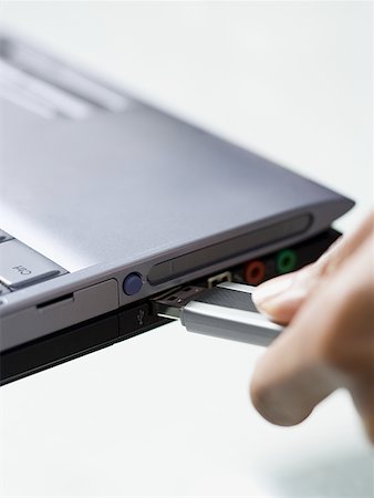 Close-up of a person's hand connecting a jump drive to a laptop Stock Photo - Premium Royalty-Free, Code: 640-01354799