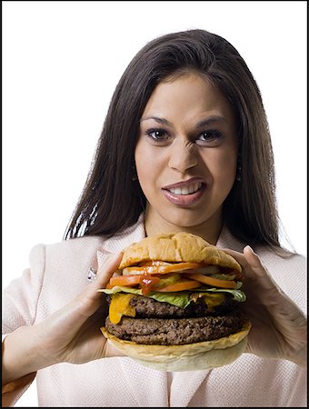 Portrait of a young woman holding a hamburger and making a face Stock Photo - Premium Royalty-Free, Code: 640-01355226