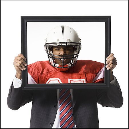 split personality - Businessman holding picture of football player with helmet Stock Photo - Premium Royalty-Free, Code: 640-01355397
