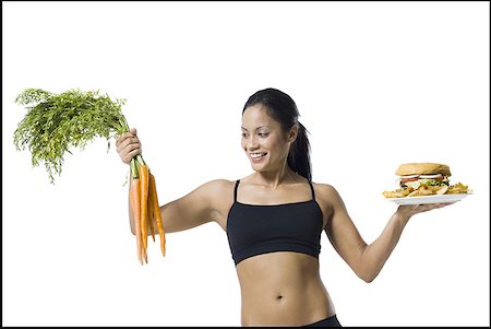 Woman choosing between carrots or hamburger Stock Photo - Premium Royalty-Free, Code: 640-01355414