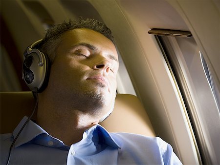 simsearch:400-04140609,k - Gros plan d'un homme d'affaires de sommeil et écouter de la musique sur le casque dans un avion Photographie de stock - Premium Libres de Droits, Code: 640-01355587