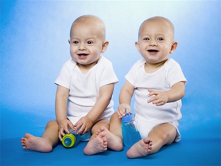 Twin babies sitting with baby bottles Stock Photo - Premium Royalty-Free, Code: 640-01355622