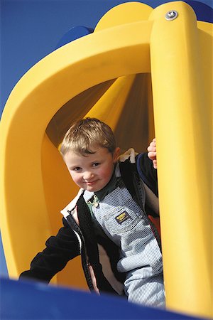 Low angle view of a young boy in a jungle gym on a playground Stock Photo - Premium Royalty-Free, Code: 640-01355754