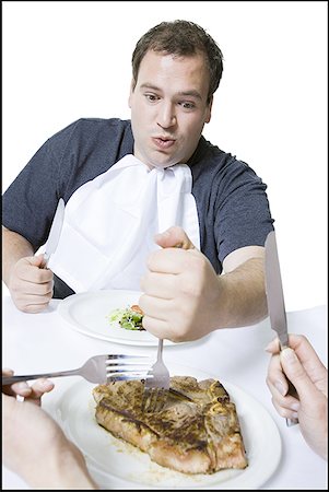 Close-up of a young man taking food from another person's plate Stock Photo - Premium Royalty-Free, Code: 640-01356052