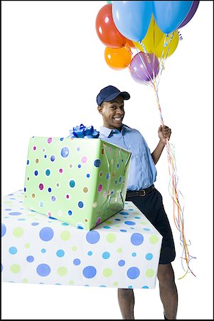 delivery african ethnicity - Portrait of a delivery man holding gifts and balloons Stock Photo - Premium Royalty-Free, Code: 640-01356107