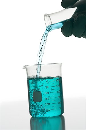 Person pouring chemical into a beaker Stock Photo - Premium Royalty-Free, Code: 640-01356365