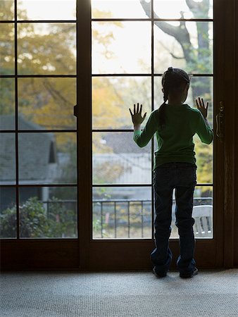 Rear view of a girl looking through a window Stock Photo - Premium Royalty-Free, Code: 640-01356367