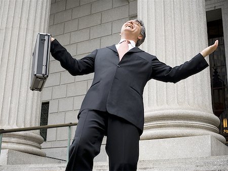 politician - Low angle view of a male lawyer holding a briefcase and laughing Stock Photo - Premium Royalty-Free, Code: 640-01356406