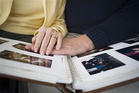 Mid section view of a couple looking at a photo album Foto de stock - Sin royalties Premium, Código: 640-01356441