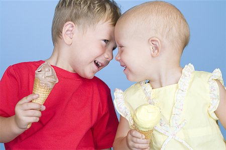 Close-up of a boy and a girl holding ice creams and smiling Stock Photo - Premium Royalty-Free, Code: 640-01356506