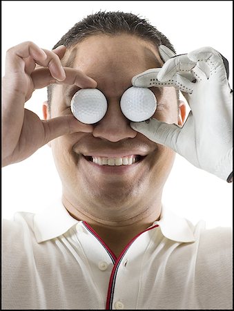 simsearch:640-03264970,k - Close-up of a mid adult man holding two golf balls in front of his eyes Stock Photo - Premium Royalty-Free, Code: 640-01356737