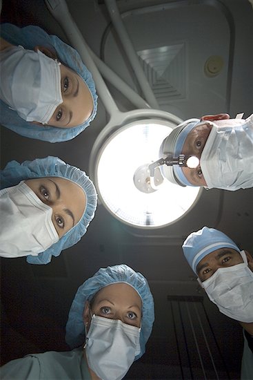 Low-angle view of five surgeons standing over an operating table Stock Photo - Premium Royalty-Free, Image code: 640-01356785