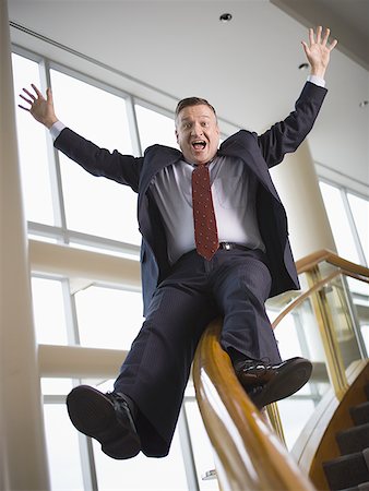 slide business man - Happy businessman sliding down stair railing Stock Photo - Premium Royalty-Free, Code: 640-01356804