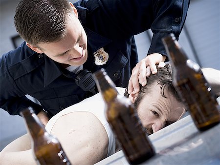 simsearch:640-01351574,k - Police officer arresting man lying down with beer bottles Fotografie stock - Premium Royalty-Free, Codice: 640-01357120