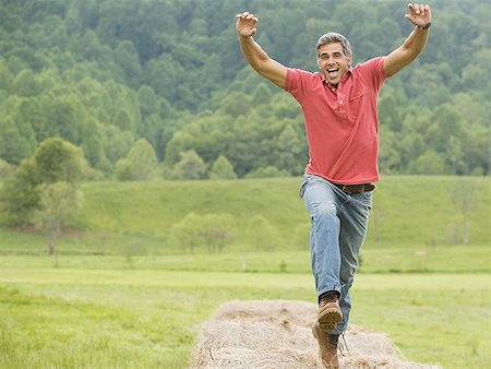 ecstatic - Portrait of a man jumping on a hay bale Stock Photo - Premium Royalty-Free, Code: 640-01357144