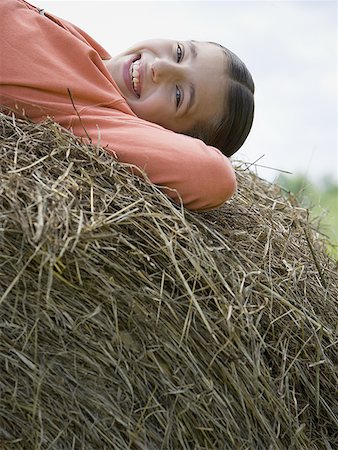 Portrait of a girl lying on a hay bale Stock Photo - Premium Royalty-Free, Code: 640-01357386