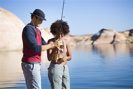 Young man teaching a young woman how to fish Stock Photo - Premium Royalty-Free, Code: 640-01357674