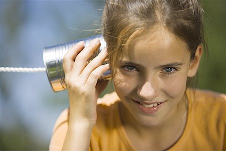 string lights fun - Portrait of a girl listening into a tin can phone Stock Photo - Premium Royalty-Free, Code: 640-01357698