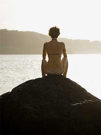 Young woman sitting on a rock at sunset Foto de stock - Sin royalties Premium, Código: 640-01357725