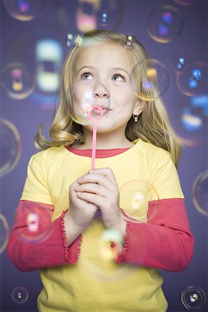 Gros plan d'une jeune fille soufflant des bulles avec une baguette à bulles Photographie de stock - Premium Libres de Droits, Code: 640-01357783