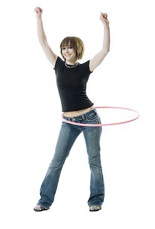 Portrait of a teenage girl spinning a hula hoop around her waist Stock Photo - Premium Royalty-Free, Code: 640-01357842