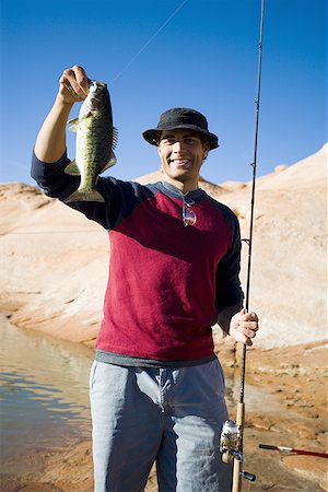 Jeune homme tenant un poisson avec une canne à pêche Photographie de stock - Premium Libres de Droits, Code: 640-01357970