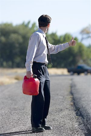 roadside assistance - Man hitchhiking while holding a gas can Stock Photo - Premium Royalty-Free, Code: 640-01358018