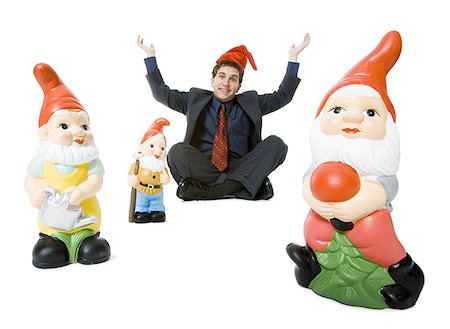 Portrait of a businessman sitting with three garden gnomes Stock Photo - Premium Royalty-Free, Code: 640-01358118