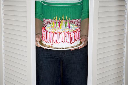 Mid section view of a woman holding a birthday cake Stock Photo - Premium Royalty-Free, Code: 640-01358120