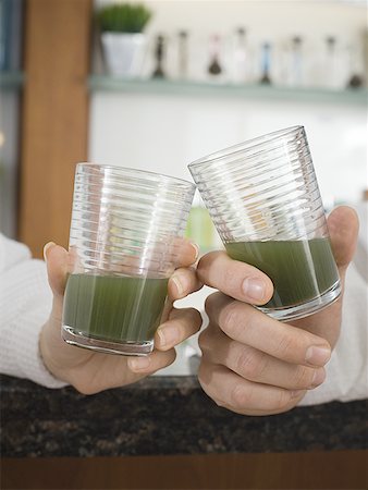 Close-up of two person's hands toasting with glasses of wheatgrass juice Stock Photo - Premium Royalty-Free, Code: 640-01358249