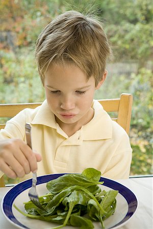 Close-up of a boy eating spinach with a fork Stock Photo - Premium Royalty-Free, Code: 640-01358266