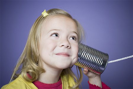 Close-up of a girl listening to a tin can phone Stock Photo - Premium Royalty-Free, Code: 640-01358275