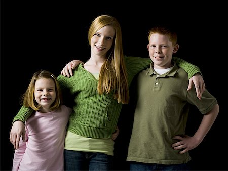 Portrait of a teenage girl with boy and young girl embracing and smiling Stock Photo - Premium Royalty-Free, Code: 640-01358397