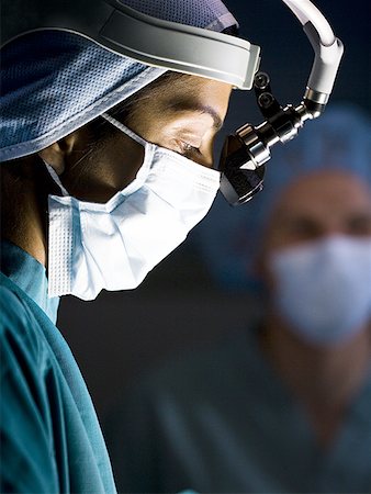 Female doctor in scrubs with head light in surgery Stock Photo - Premium Royalty-Free, Code: 640-01358393